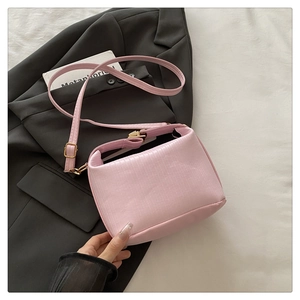 Detail of pink PU leather handbag with vertical pleated texture and gold metal buckle