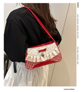 Detail of red gingham mini bag with heart prints, silver heart charm and ruffled trim