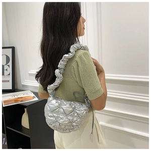 Detail of silver metallic quilted shoulder bag with cloud-style pleated strap worn by model
