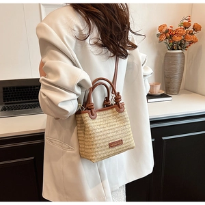 Detailed texture of beige woven straw tote bag with brown leather handles and shoulder strap