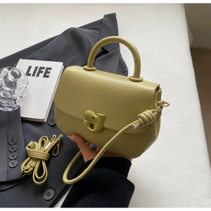 Détail du sac selle en cuir vert clair avec boucle magnétique et bandoulière amovible