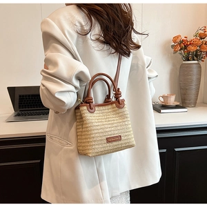 Close-up of woven straw texture with brown leather handles and brand logo tag
