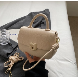 Détail du sac selle en cuir grainé beige avec boucle magnétique unique en forme de g