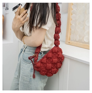 Detail of red quilted puffer shoulder bag featuring soft textured nylon and padded wide strap