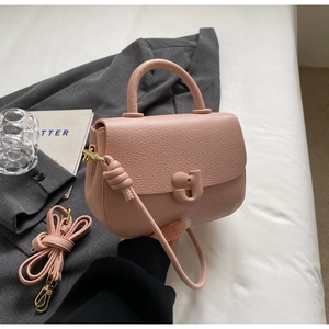 Détail du sac selle en cuir grainé rose avec boucle en G et bandoulière réglable