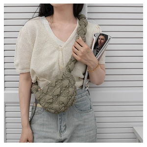 Detail view of olive green cloud bag with puffy quilted texture on model shoulder