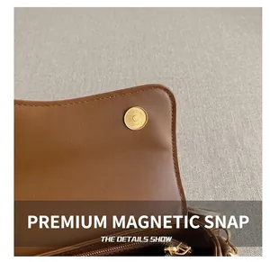 Détail d'un sac en cuir marron montrant une boucle magnétique dorée et une fermeture éclair