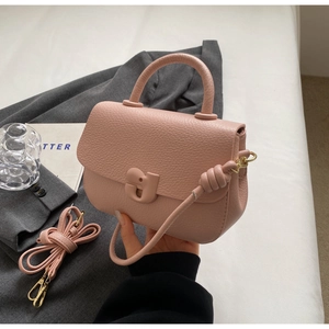 Détail du sac selle en cuir grainé rose clair montrant les finitions dorées et l'anse