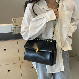 Structured black leather tote with gold chain strap and square metal lock on a model
