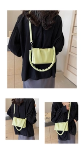 Detail of light green pleated handbag with chunky handle and silver metal hardware