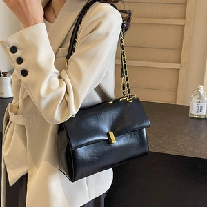 Classic black chain shoulder bag with gold hardware worn over a beige blazer outfit