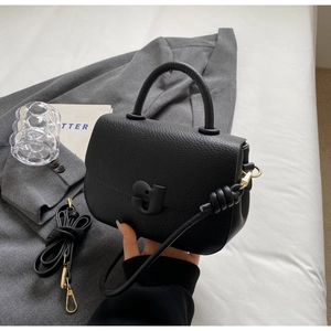 Détail du sac selle en cuir grainé noir avec boucle dorée et poignée supérieure
