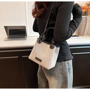 Canvas bucket bag with leather trim held by a model in a modern office setting