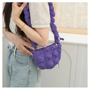 Detail of purple quilted puff dumpling bag with ruched texture and wide shoulder strap