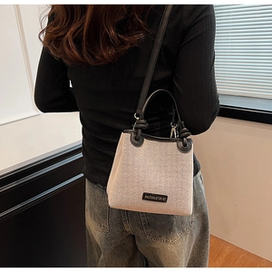 Detail of minimalist canvas and black leather patchwork tote showing the brand logo