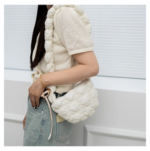 Close-up of beige quilted cloud bag with padded nylon texture and shoulder strap detail