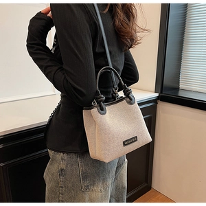 Detail of canvas bucket bag with black leather trim worn on shoulder for commuting