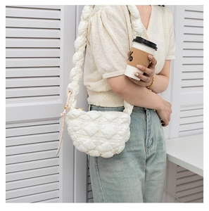 Detail view of white quilted puffer bag featuring soft cloud texture and crescent shape