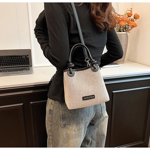Detail shot of canvas shoulder bag with black leather trim and detachable strap