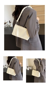 Detail of white pleated shoulder bag with soft ruched strap over a grey blazer