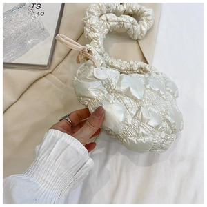 Detailed view of white quilted shoulder bag with ruffled strap and soft cloud texture