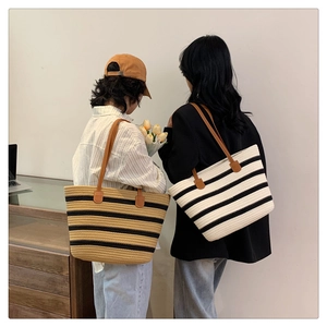 Detailed close-up of striped woven tote bag with premium brown leather shoulder straps