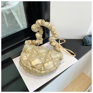 Detail of metallic gold quilted puffy bag with ruched handle and diamond stitching texture