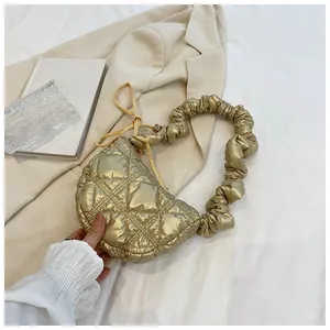 Detail of metallic gold quilted crescent bag with a trendy scrunchie cloud handle design