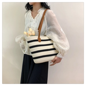 Detail of woven cotton tote bag with black stripes and brown leather handles