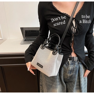 Detail of mini canvas bucket bag with black leather trim worn on the shoulder