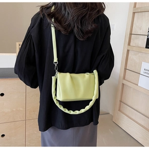 Avocado green pleated bag worn as a shoulder bag showing the drape and compact size