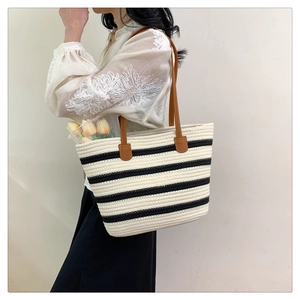 Detailed side view of black and white striped woven tote bag with brown shoulder straps
