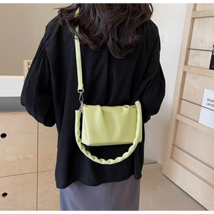 Detail of avocado green pleated crossbody bag with thick twisted handle shown on model