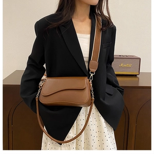 Sacoche marron vintage en cuir avec large bandoulière et chaîne dorée sur mannequin