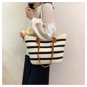 Close-up of black and white striped woven tote bag with premium brown leather straps