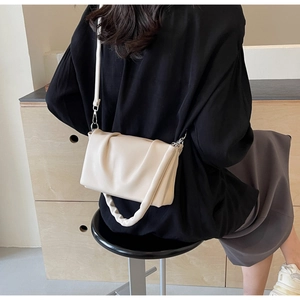 Close-up of cream pleated cloud bag showing soft leather texture and handle detail