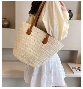 Detailed texture of off-white woven straw tote with premium brown leather shoulder straps