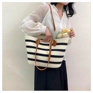 Detail of striped woven cotton bag with leather straps on model shoulder
