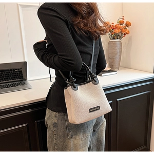 Detail of a chic beige woven tote bag with black leather trim worn by a model in office