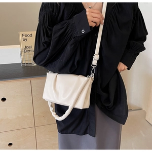 Detail of creamy white pleated crossbody bag with soft texture and adjustable straps