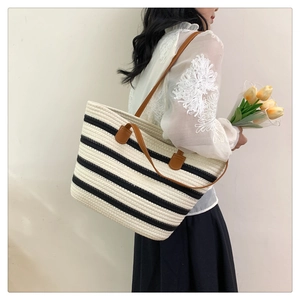 Detail of black and white striped woven tote with premium brown leather straps on model