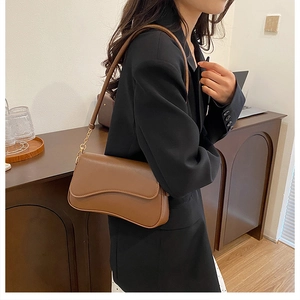 Détail d'un sac bandoulière marron en similicuir avec rabat asymétrique et chaîne