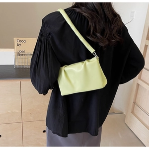 Light green pleated shoulder bag with wide strap styled on a minimalist model