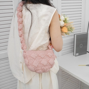 Pink quilted puffer dumpling bag with soft ruched shoulder strap worn by a female model