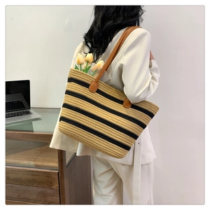 Close-up of woven cotton rope tote bag with black and yellow stripes and leather straps