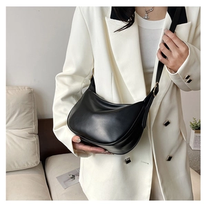 Detail of minimalist black PU crescent bag with adjustable metal buckle on shoulder strap
