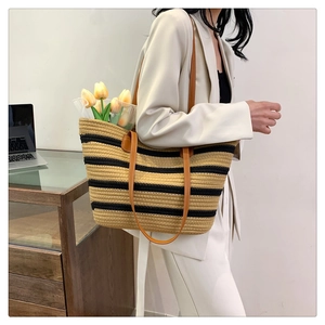 Detail of striped woven cotton tote bag with premium brown leather handles for beach