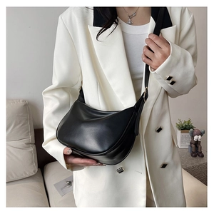 Detail of adjustable leather strap and gold buckle on a black PU crescent shoulder bag