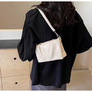 Close-up of cream pleated shoulder bag featuring soft leather texture and silver buckle