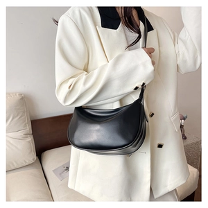Close-up of black PU leather crescent moon shoulder bag on model in white blazer